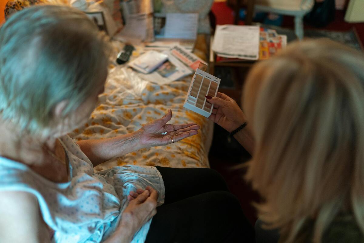 pečující žena podává seniorce léky