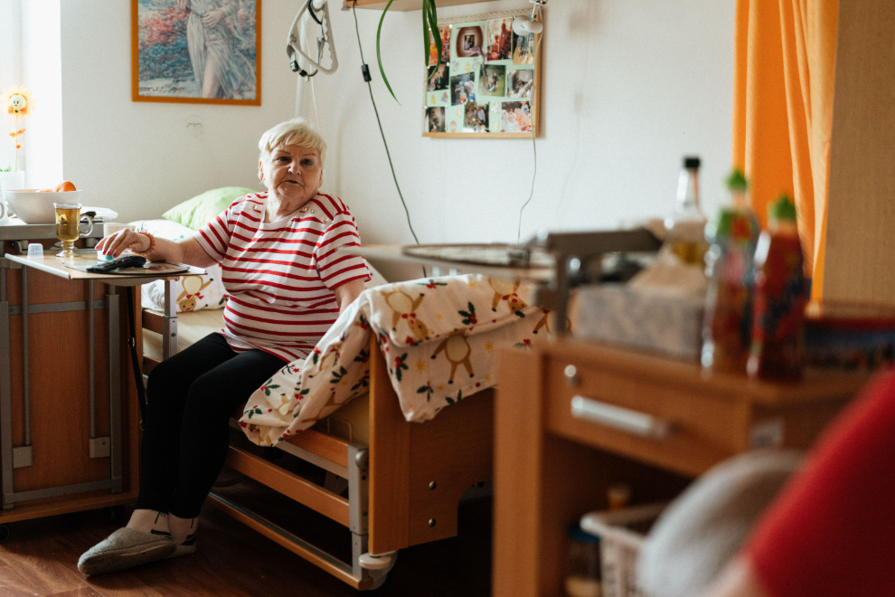 seniorka sedící na polohovací posteli v domě pro seniory