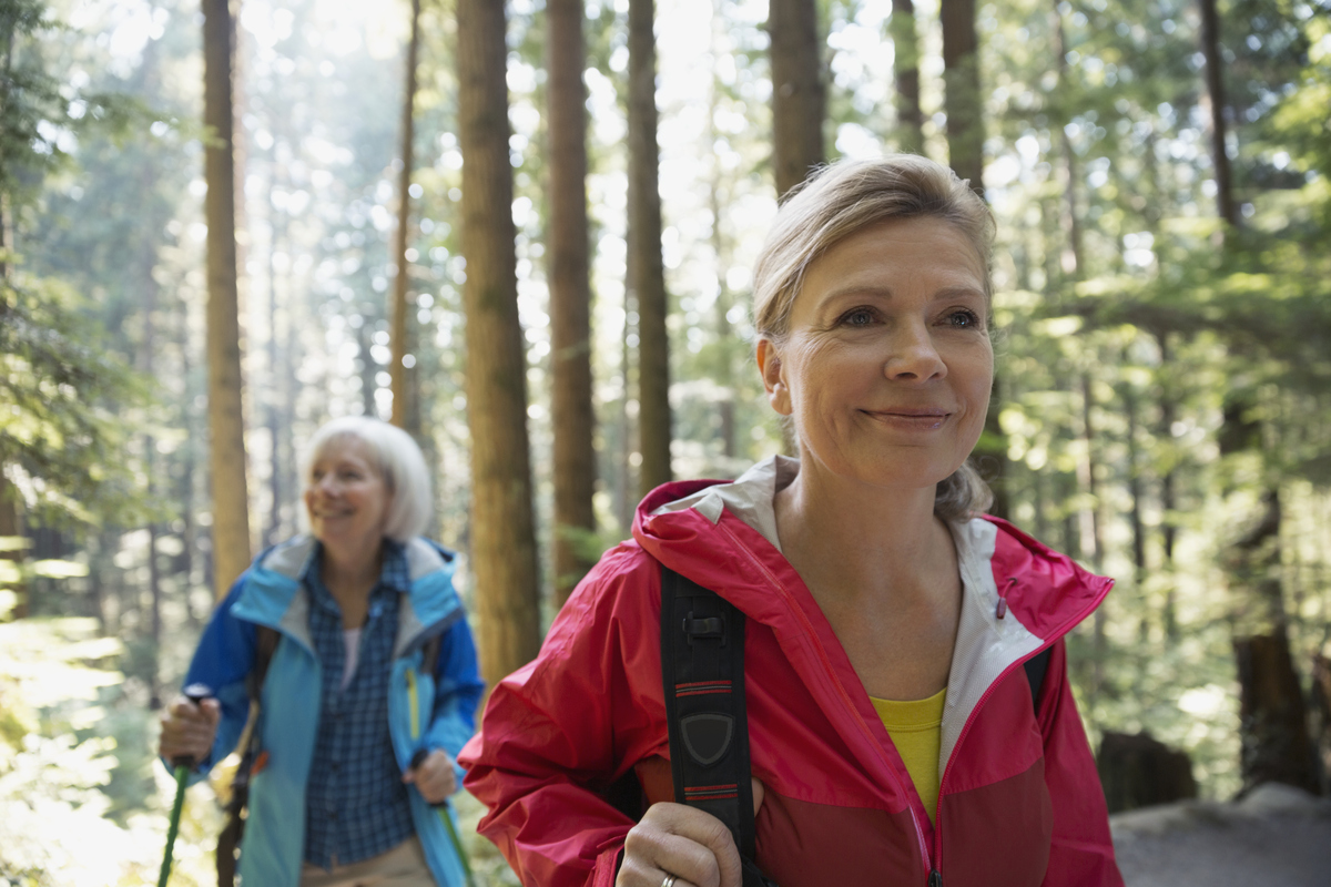 mladší a starší žena na procházce lesem s hůlkami na nordic walking