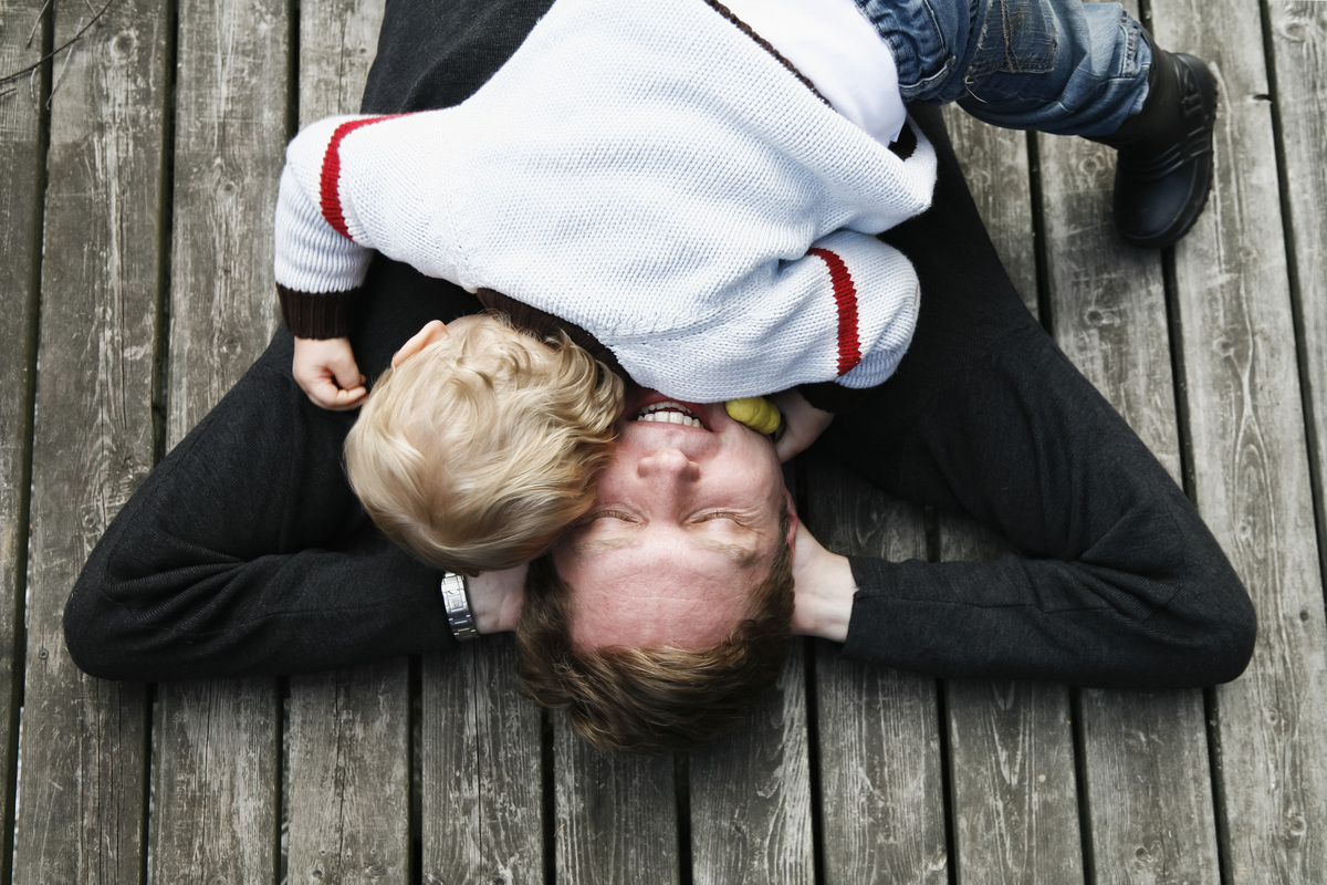muž se synem leží na dřevené podlaze