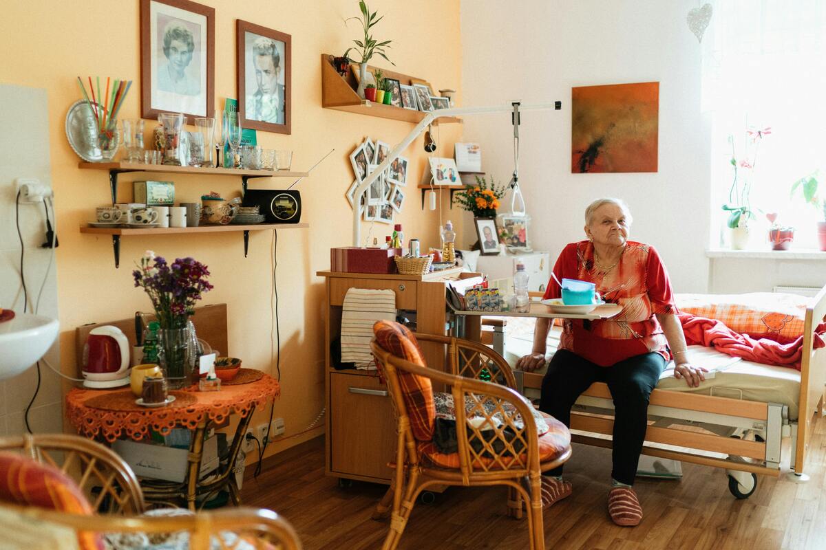 starší žena sedící na posteli v zařízení pro seniory
