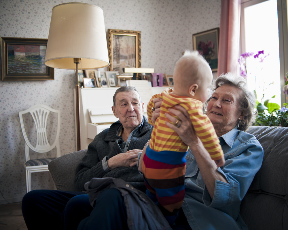 prarodiče sedí na gauči a babička chová vnoučka